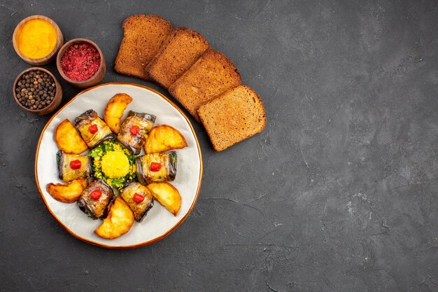 Vista dall'alto deliziosi involtini di melanzane piatto cotto con pane di patate e condimenti sullo sfondo scuro piatto per cucinare cibo fritto di patate cuocere