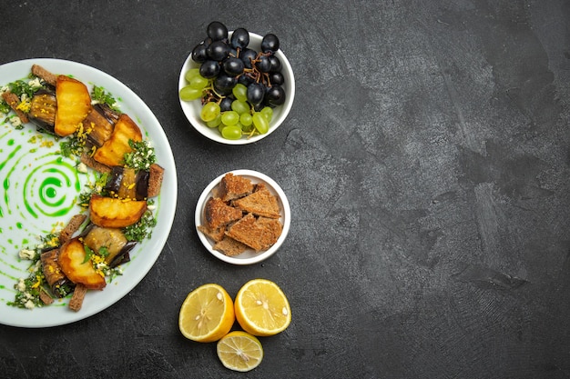 Вид сверху вкусные рулетики из баклажанов с печеным картофелем внутри тарелки на темном фоне блюдо ужин еда картофель овощ