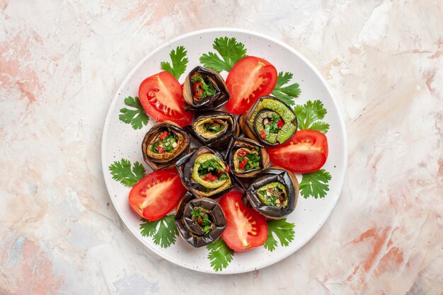 Top view delicious eggplant rolls with greens and tomatoes