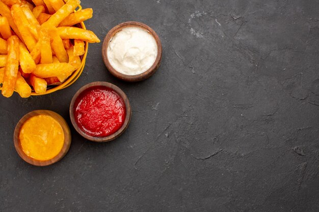 Top view delicious french fries with ketchup mustard and mayyonaise on dark background burger fast-food potato dish meal