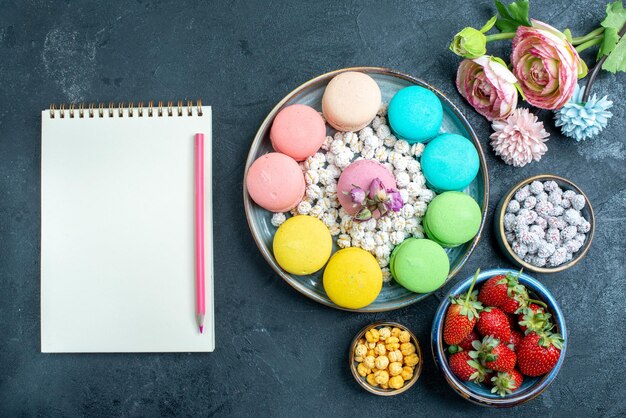 Top view delicious french macarons with candies inside tray on the dark space