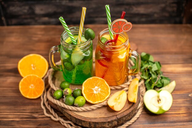 Top view of delicious fresh juices and fruits on a wooden tray on a brown background