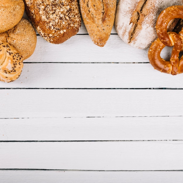 Foto gratuita vista superiore di delizioso pane appena sfornato su fondo di legno