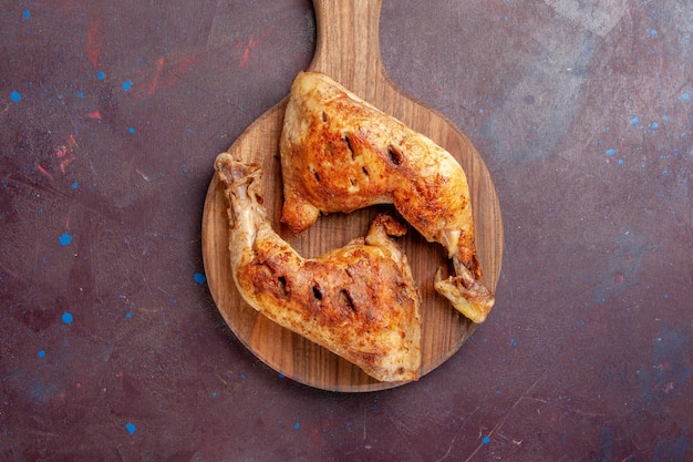 Вид сверху вкусной жареной курицы, приготовленных кусочками мяса на темном столе