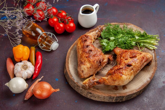 Вид сверху вкусной жареной курицы со свежими овощами и зеленью на темном столе