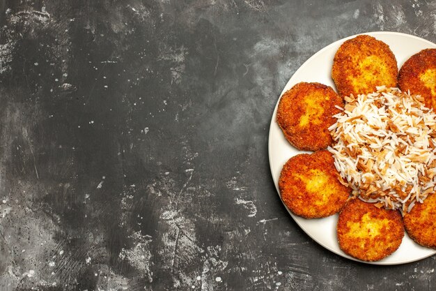 Top view delicious fried cutlets with cooked rice on dark desk meat dish photo meal