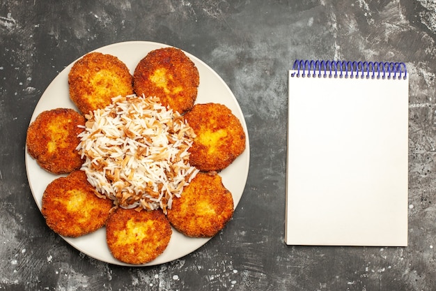 Vista dall'alto deliziose cotolette fritte con riso cotto su un piatto di carne scura foto pasto