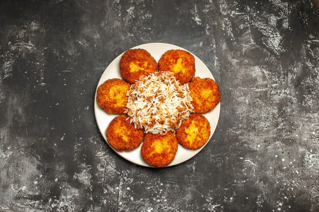 Top view delicious fried cutlets with cooked rice on a dark surface meat dish photo meal