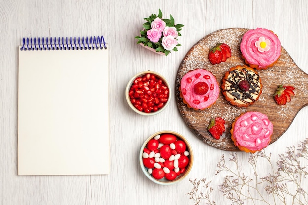 Free photo top view delicious fruit cakes creamy desserts with candies and fruits on white background cream sweet cookie dessert cake tea