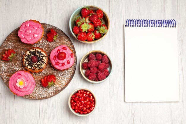 Top view delicious fruit cakes creamy desserts with fruits and berries on the white background cream tea sweet cake cookie dessert