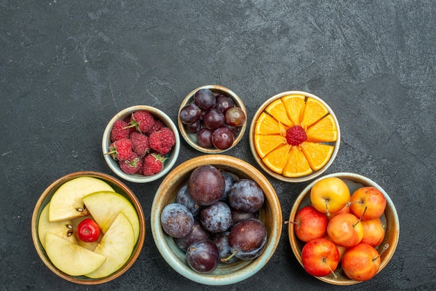 Free photo top view delicious fruit composition fresh fruits on dark background ripe fresh health diet fruits mellow