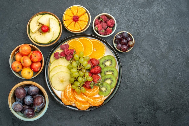 Top view delicious fruit composition fresh and sliced fruits on the dark background ripe fresh health diet fruit mellow