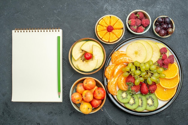 Top view delicious fruit composition fresh and sliced fruits on the dark background ripe fresh health fruit mellow