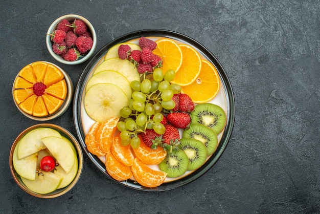 Вид сверху вкусной фруктовой композиции, свежих нарезанных и спелых фруктов на темном фоне, свежая здоровая диета, спелые фрукты