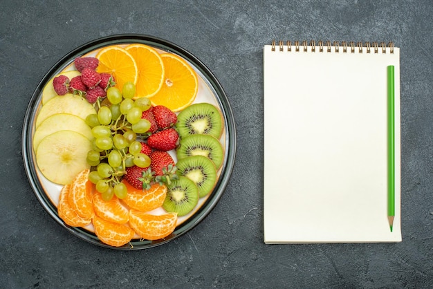 Top view delicious fruit composition fresh sliced and mellow fruits on dark background ripe fresh mellow health diet fruit