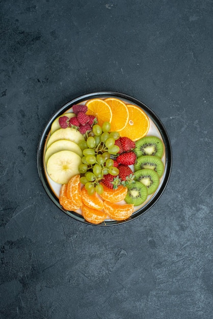 Foto gratuita vista dall'alto deliziosa composizione di frutta fresca affettata e frutta dolce sullo sfondo scuro dieta salutare fresca e matura