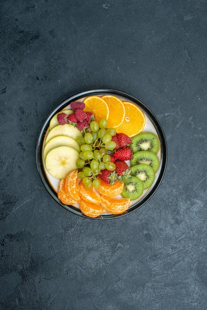 Vista dall'alto deliziosa composizione di frutta fresca affettata e frutta dolce sullo sfondo scuro dieta salutare fresca e matura