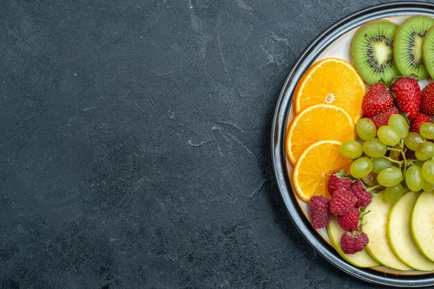 Top view delicious fruit composition fresh sliced and mellow fruits on dark desk ripe fresh mellow health diet