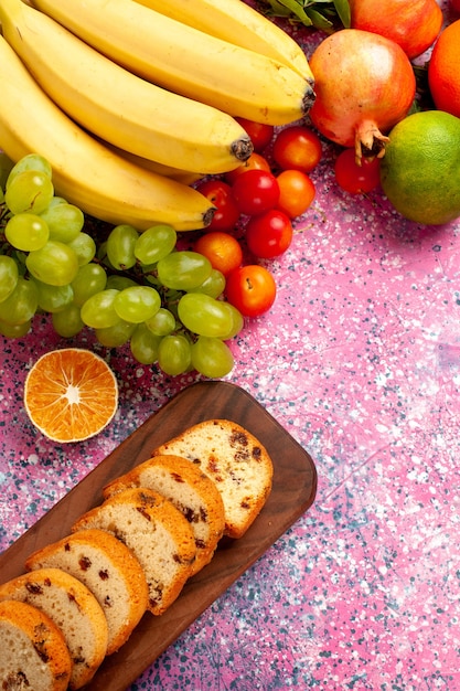 Foto gratuita vista dall'alto deliziosa composizione di frutta con torte a fette sulla scrivania rosa