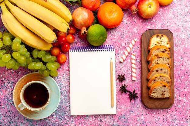 Вид сверху вкусной фруктовой композиции с нарезанными тортами и чаем на розовом столе