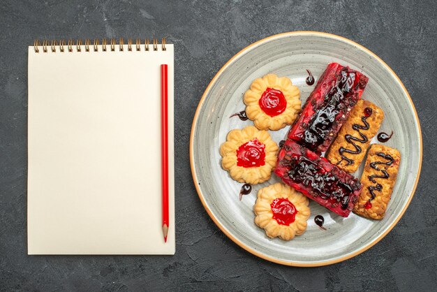 灰色の机の上のクッキーとおいしいフルーティーなケーキの上面図ビスケットケーキクッキークッキー甘い
