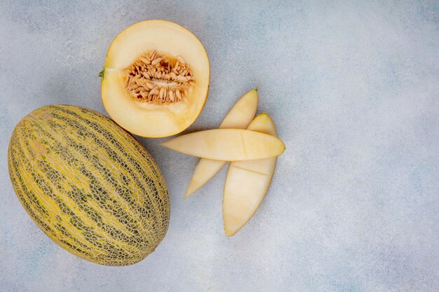 Top view of delicious halved and whole cantaloupe melon with peels on white with copy space