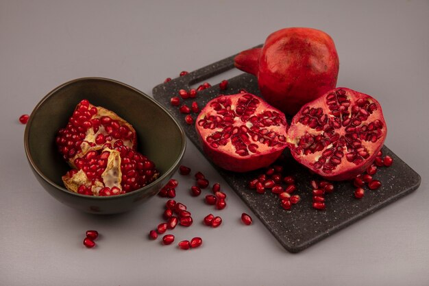 Top view of delicious halved and whole pomegranates on a black kitchen board with open pomegranates on a bowl