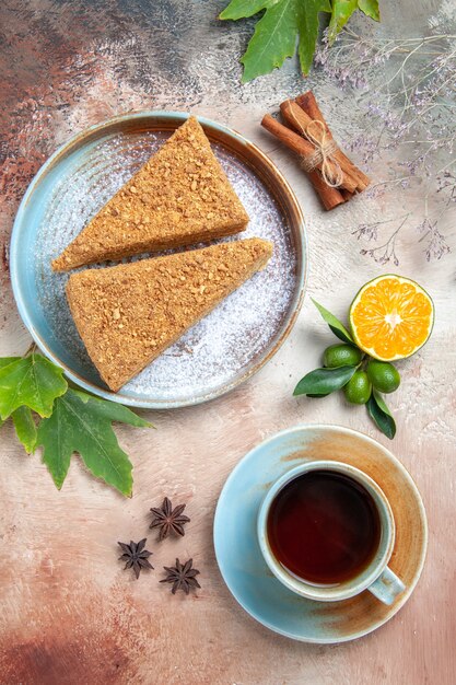 Top view delicious honey cake with cup of tea on light floor cake pie biscuit sweet