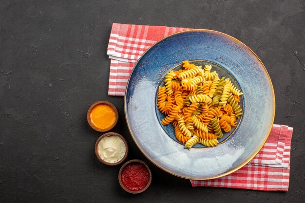 Top view delicious italian pasta unusual cooked spiral pasta on the dark background pasta dish meal cooking dinner