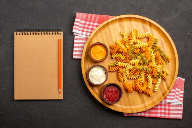 Top view delicious italian pasta unusual cooked spiral pasta with seasonings on dark background dish meal cooking pasta