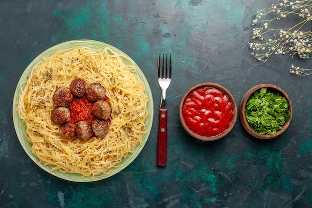 Foto gratuita vista dall'alto deliziosa pasta italiana con polpette di carne e salsa di pomodoro sulla scrivania blu scuro pasta pasta cibo pasto piatto cena