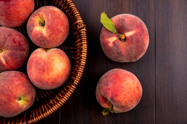 Free photo top view of delicious and juicy peaches on bucket on wood