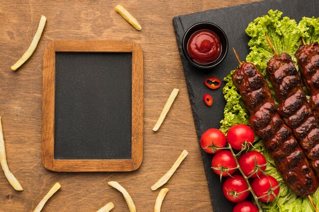 Top view of delicious kebab on slate with frame and french fries