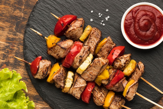 Top view of delicious kebab on slate with salad and ketchup