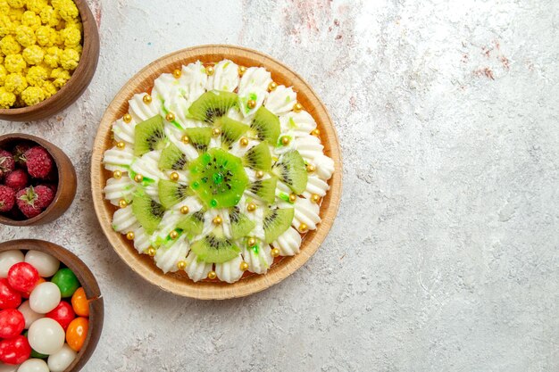 Вид сверху вкусный десерт киви с конфетами на светлом белом фоне десертный торт крем фруктовый тропический