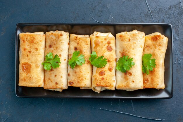 진한 파란색 배경에 검은 접시에 맛있는 lavash 랩의 상위 뷰