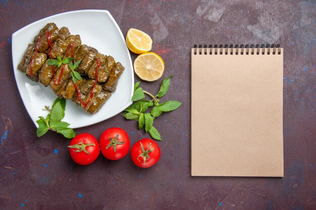 Foto gratuita vista dall'alto deliziosa foglia di dolma piatto di carne macinata con limone e pomodori sullo sfondo scuro piatto di foglie di cena cibo carne dinner