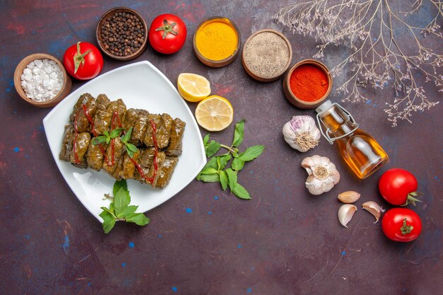 Top view delicious leaf dolma with different seasonings and tomatoes on a dark background meat dish leaf food dinner