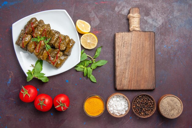 Top view delicious leaf dolma with lemon seasonings and tomatoes on dark background dish leaf dinner food meat