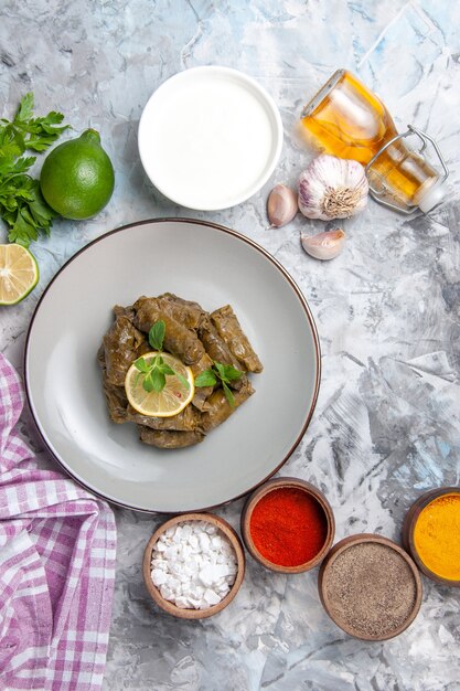 Вид сверху вкусной листовой долмы с приправами на белой поверхности