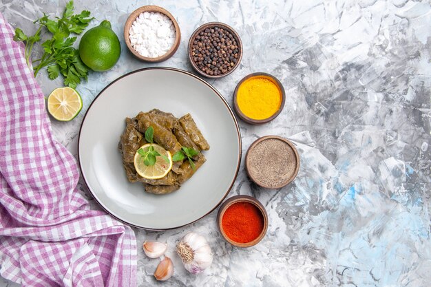 Top view of delicious leaf dolma with seasonings on white surface