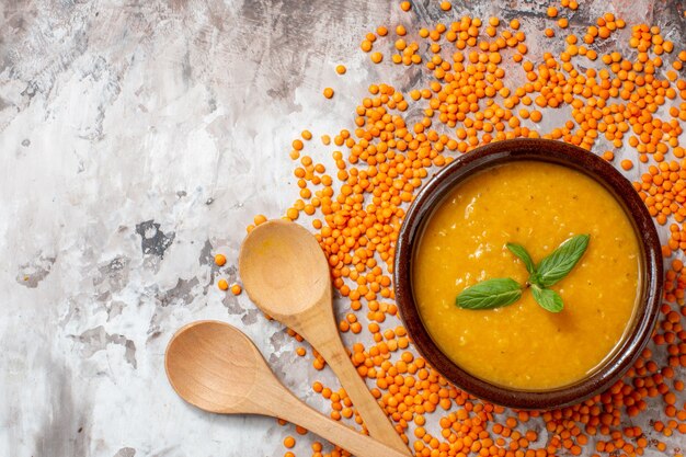 Top view delicious lentils soup with raw lentils on light background plant soup color photo food seed dish