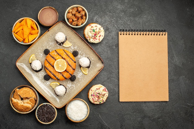 Free photo top view delicious little cake with coconut candies on a dark-grey background cake dessert biscuit pie cookie tea