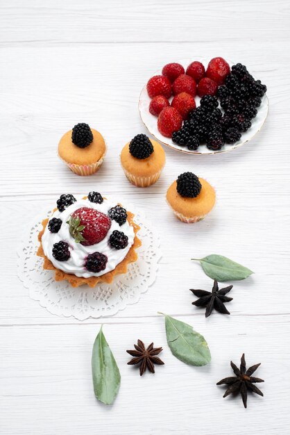 Top view of delicious little cake with cream and berries cookies on white desk, cake biscuit bake fruit sweet sugar berry