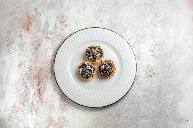 Top view delicious little cakes with chocolate chips inside plate on white background cake biscuit sweet cream tea dessert