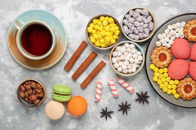 Top view delicious little cakes with cookies and candies on the white surface sugar cake bake biscuit pie tea cookie