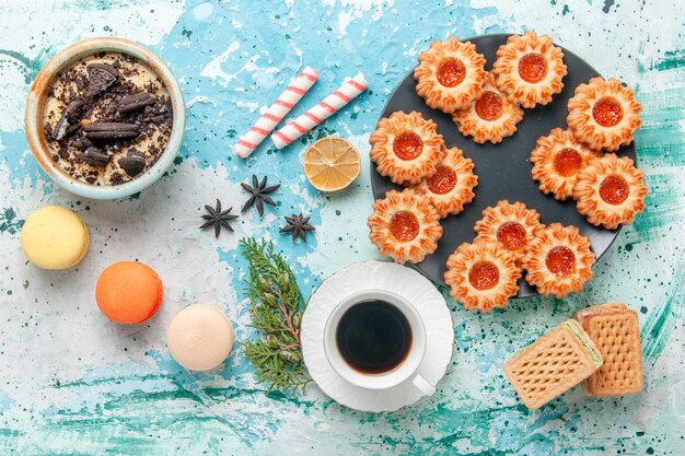 Top view delicious little cookies with cup of coffee macarons and waffles on the blue desk cookie biscuit sweet sugar color tea