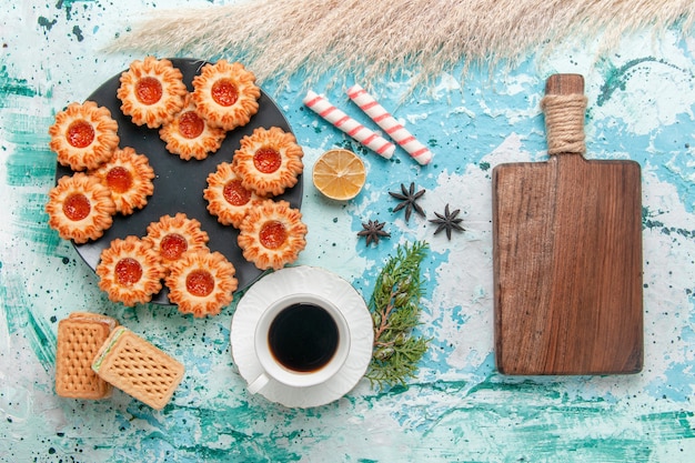 Foto gratuita vista dall'alto deliziosi piccoli biscotti con una tazza di caffè e cialde sulla scrivania blu biscotto biscotto dolce zucchero colore tè