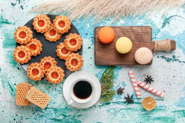 Top view delicious little cookies with waffles macarons and cup of coffee on blue desk cookie biscuit sweet sugar color tea