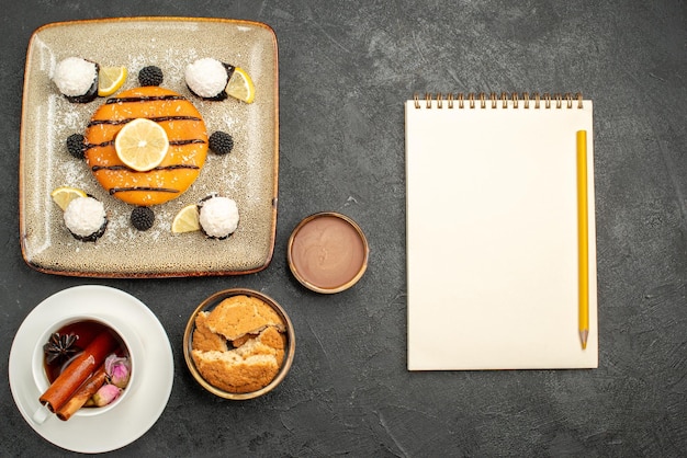 Top view delicious little pie with coconut candies and cup of tea on a dark background candy biscuit cake pie cookie sweet